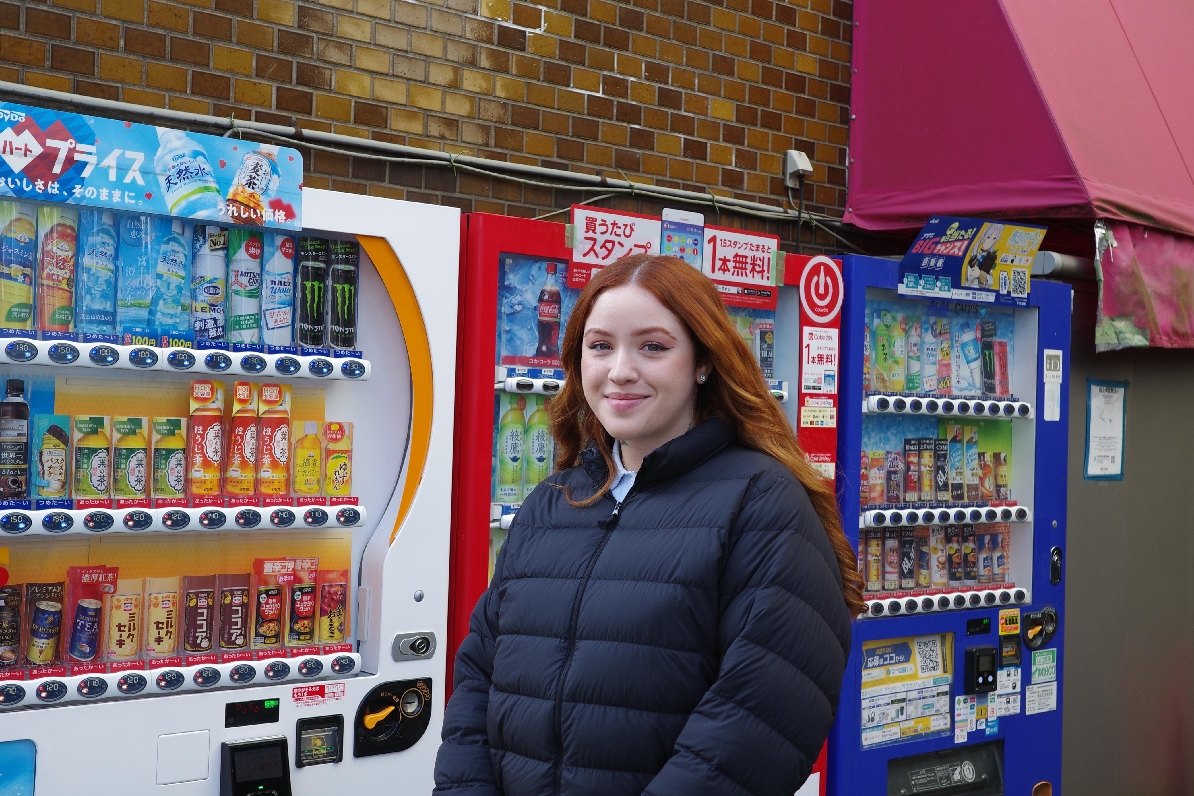 Giovanna standing in front of vending machines in Japan